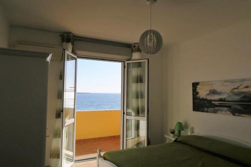 a bedroom with a bed and a view of the ocean at Appartamenti Sole in Alghero