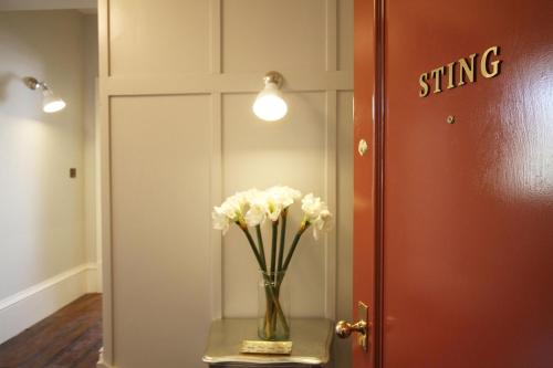 wazon z białymi kwiatami na stole obok drzwi w obiekcie Old Bank Apartments w mieście Stamford