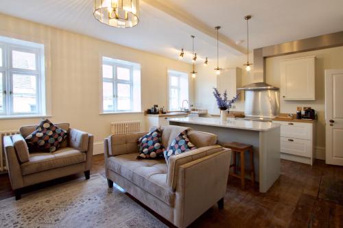 a living room with two chairs and a couch and a kitchen at Old Bank Apartments in Stamford
