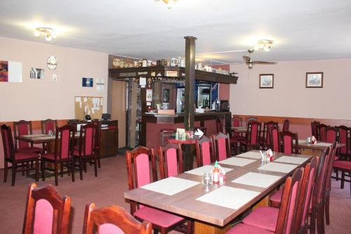 a dining room with tables and chairs and a bar at Penzion Avena in Stříbro