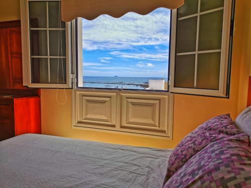 1 dormitorio con ventana y vistas al océano en Apartamentos Brito, en Orzola