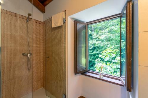 a bathroom with a shower and a window at Casas del Molino - Muiños do Mainzoso Turismo Rural in Paderne