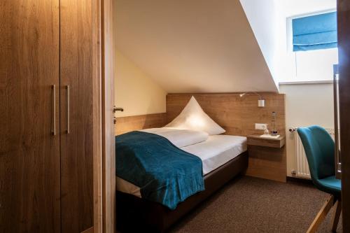 een kleine slaapkamer met een bed en een stoel bij Gasthof Hotel Drei Tannen Altdorf in Altdorf