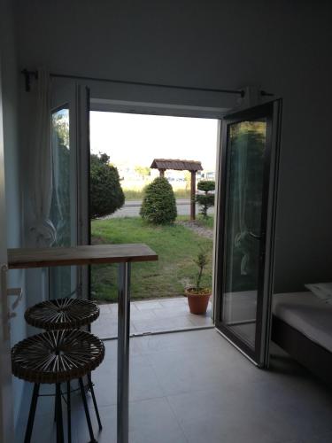 a glass door leading to a patio with a table and two stools at Pokoj dwuosobowy hotelowy in Łeba