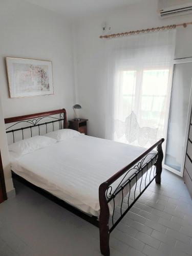 a bedroom with a large bed with white sheets and a window at Maisonette with Garden& Parking Polichrono in Polychrono