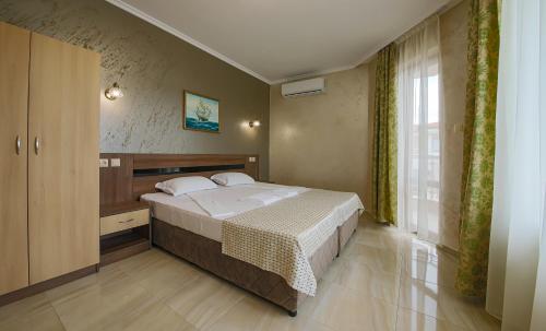 a bedroom with a bed and a large window at Guesthouse Phoenix in Obzor