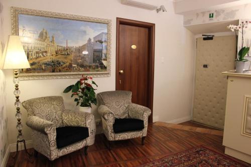 a hallway with two chairs and a painting on the wall at Locanda Navona in Rome