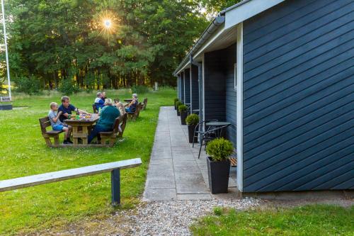 a group of people sitting at a table outside a building at Ansager Hotel og Hytteby in Ansager