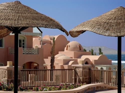 two straw umbrellas in front of a building at Radisson Blu Resort El Quseir in Quseir