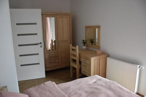 a bedroom with a desk and a dresser and a mirror at Klara - Harmonia Oliwska in Gdańsk