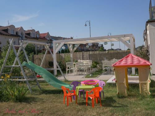 un parque infantil con sillas coloridas y un tobogán en Villa del Mar en Łeba