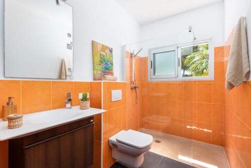 an orange bathroom with a toilet and a sink at Villa Orquidea in Son Bou