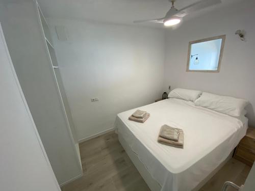 um quarto com uma cama branca com duas toalhas em Casa de Playa em Estepona