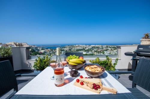 a table with a bottle of wine and a bowl of fruit at Artist Terrace Apartments in Mellieħa