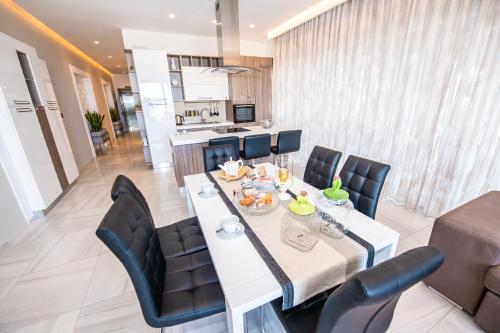 a dining room with a white table and black chairs at Artist Terrace Apartments in Mellieħa