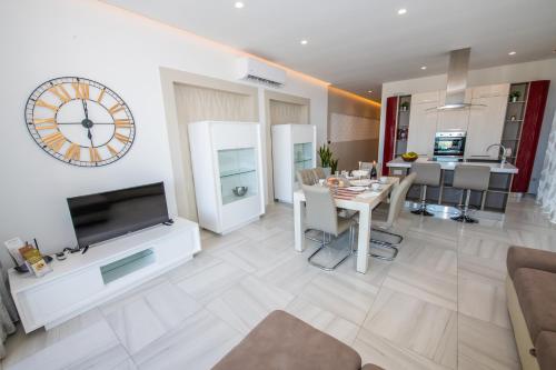 a living room with a table and a clock on the wall at Artist Terrace Apartments in Mellieħa