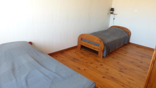 a bedroom with two beds and a wooden floor at Maison de la Delle in Pertheville-Ners