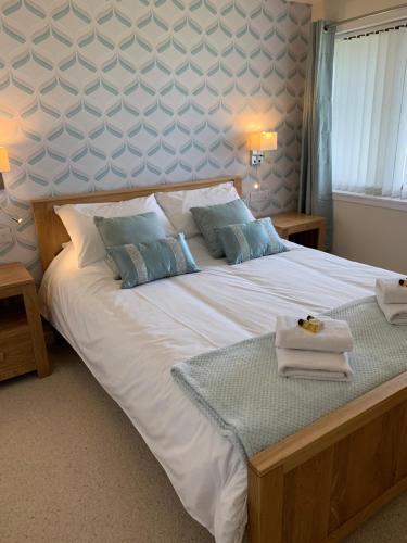 a bedroom with a large white bed with blue pillows at Greenfield Cottage in Thrumster