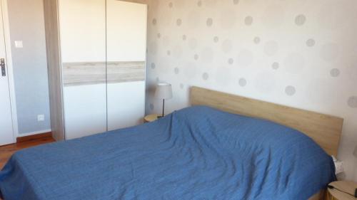 a bedroom with a blue bed and a window at Maison de la Delle in Pertheville-Ners
