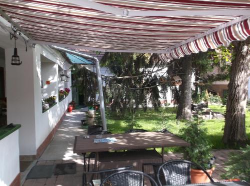 a patio with a table and chairs under a pergola at Vali Vendégház in Gyula