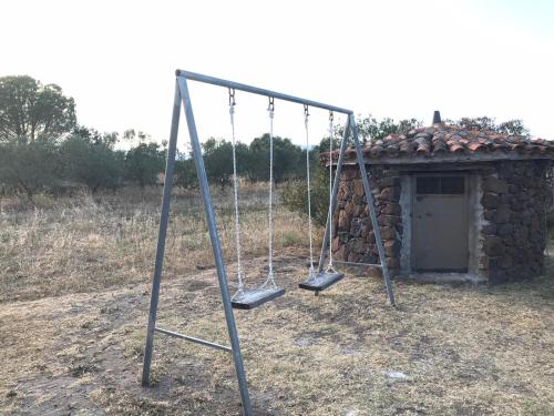 an old swing set in front of a stone building at VILLA LUPINO in Orosei
