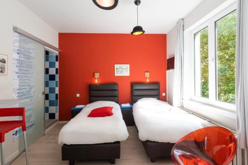 two beds in a room with a red wall at Fred&Breakfast in Ghent