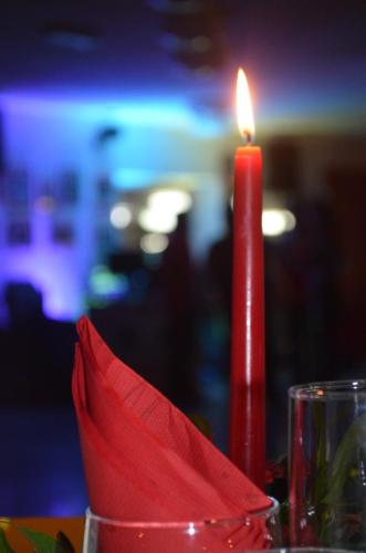 a red candle sitting on a table next to a glass at Hotel Palmarosa in Roseto degli Abruzzi