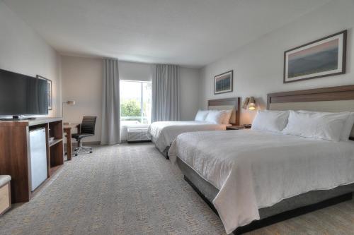a hotel room with two beds and a flat screen tv at Holiday Inn & Suites Pigeon Forge Convention Center by IHG in Pigeon Forge