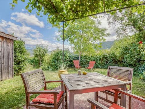 een houten tafel met twee stoelen en een schommel bij Cosy holiday home with garden in Ponet-et-Saint-Auban
