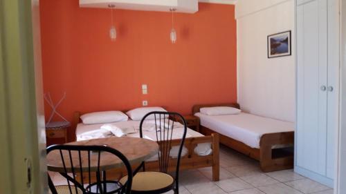 a room with two beds and a table and chairs at Homer Studio in Nydri