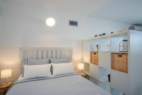 a bedroom with a bed with white walls and white shelves at A White Cliffside Studio in Pag