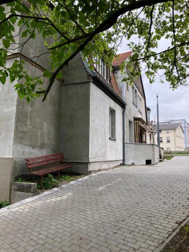 a bench sitting next to a building next to a street at Joyful Apartments Sopot in Sopot