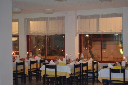 ein Esszimmer mit Tischen, Stühlen und Fenstern in der Unterkunft Hotel Palmarosa in Roseto degli Abruzzi