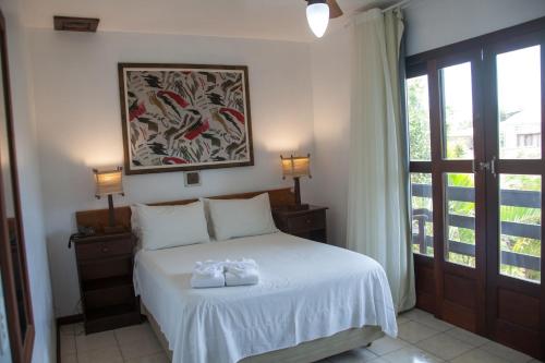 a bedroom with a bed with two white towels on it at Pousada Porto dos Casais in Praia do Rosa