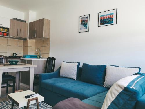 a living room with a blue couch and a kitchen at Cozy Corner Apartments - Free parking & Wi-fi in Ćuprija