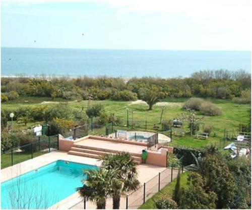 une piscine avec l'océan en arrière-plan dans l'établissement F2 - Front de Mer - Les Pieds Dans l'Eau - Appartement Situé à Saint-Cyprien Plage Sud - 30M Mer et Plage - et Non 500M- Avec Une Belle Vue sur Mer Depuis la Terrasse - Piscine - Parking Privatif - 4 Personnes, à Saint-Cyprien