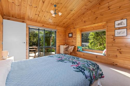 una camera con un letto in una cabina di legno di Pearl Retreat - Mangawhai Heads Holiday Home a Mangawhai