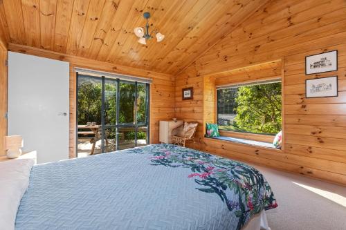 a bedroom with a bed in a wooden cabin at Pearl Retreat - Mangawhai Heads Holiday Home in Mangawhai