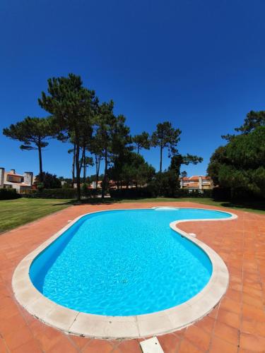 uma piscina azul com um pátio de tijolos vermelhos em Big Fish 1 - Charming Beach Apartment na Praia de Mira