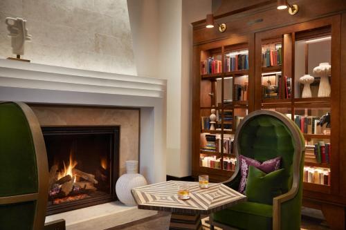 a living room with a fireplace and a green chair at The Plaza Hotel Pioneer Park in El Paso