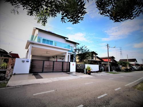 a white house with a gate on a street at Warni Villa 13 Whole Or Room in Muar