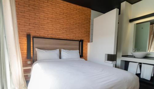 a bedroom with a white bed and a brick wall at ONOMO Hotel Dakar in Dakar