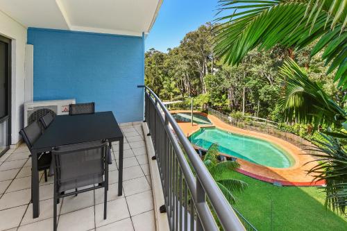 einen Balkon mit einem Tisch und einem Pool in der Unterkunft Flynns Beach Resort in Port Macquarie