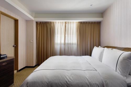 a bedroom with a large white bed and a window at K Hotel Taipei in Taipei