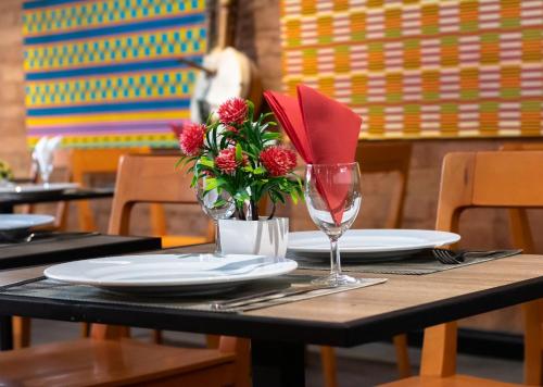a table with plates and a wine glass and flowers at ONOMO Hotel Dakar in Dakar