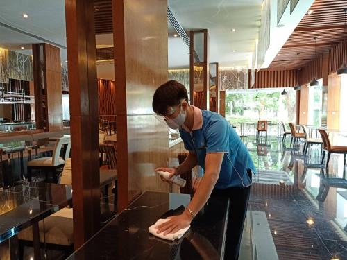 a man in a mask preparing food in a restaurant at Royal Princess Larn Luang - SHA Extra Plus in Bangkok
