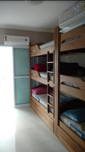 a room with four bunk beds with a door at AP Padrão Pé na Areia Centro TOP TODO COM AR CONDICIONADO in Mongaguá