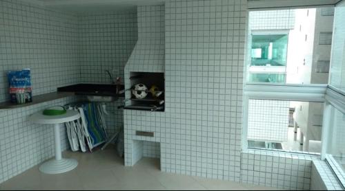 a white tiled bathroom with a table and a window at AP Padrão Pé na Areia Centro TOP TODO COM AR CONDICIONADO in Mongaguá
