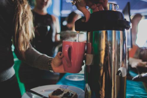 a person holding a red cup next to a coffee machine at Copenhagen Downtown Hostel in Copenhagen