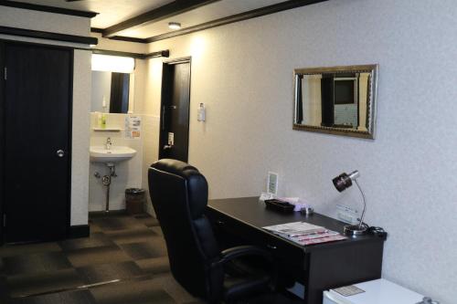 oficina con escritorio, silla y espejo en Hotel Daiki, en Osaka